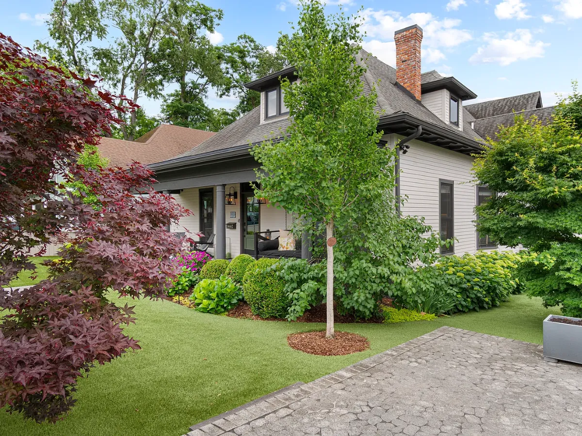 Artificial turf front lawn with planting beds and a cobblestone path at a Fort Mill, SC home