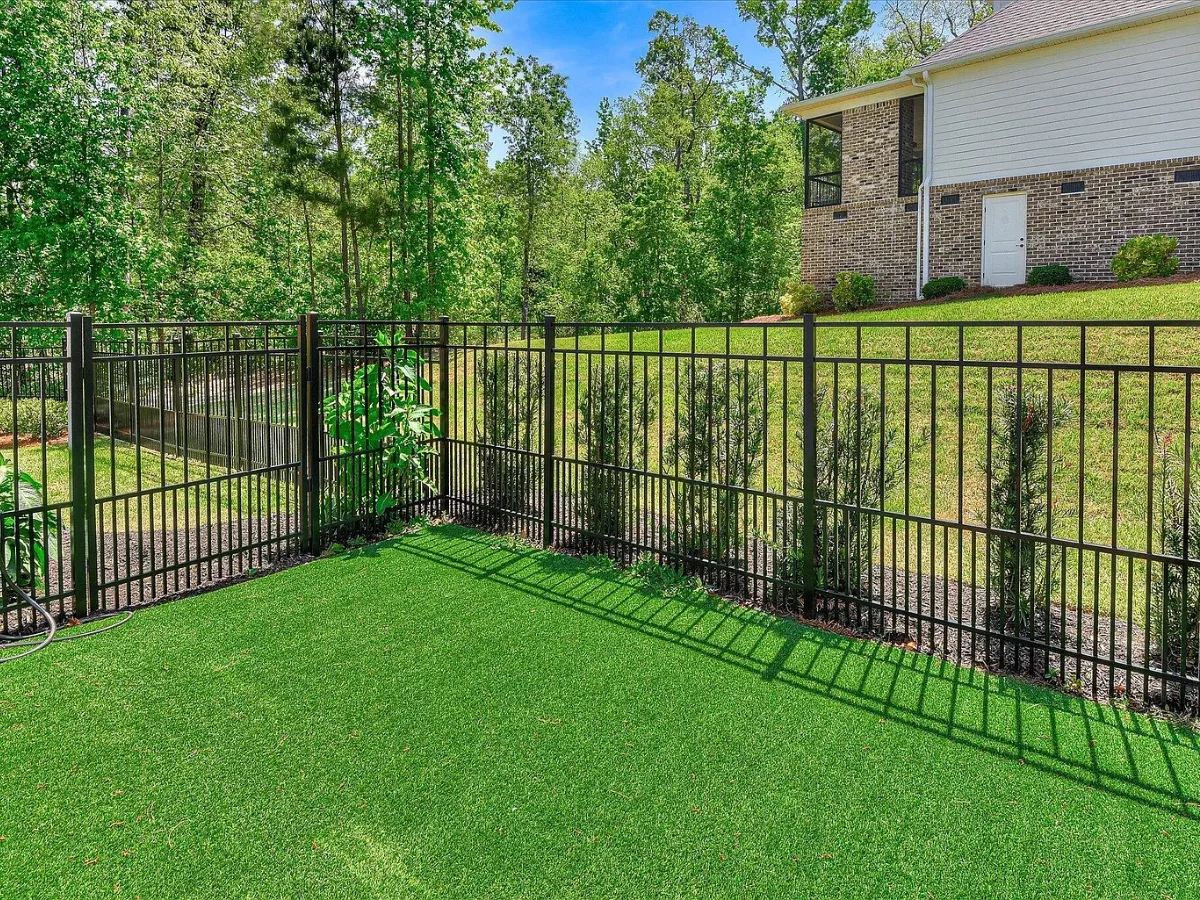 Artificial turf lawn edged along a black metal fence in a backyard in Indian Land, SC