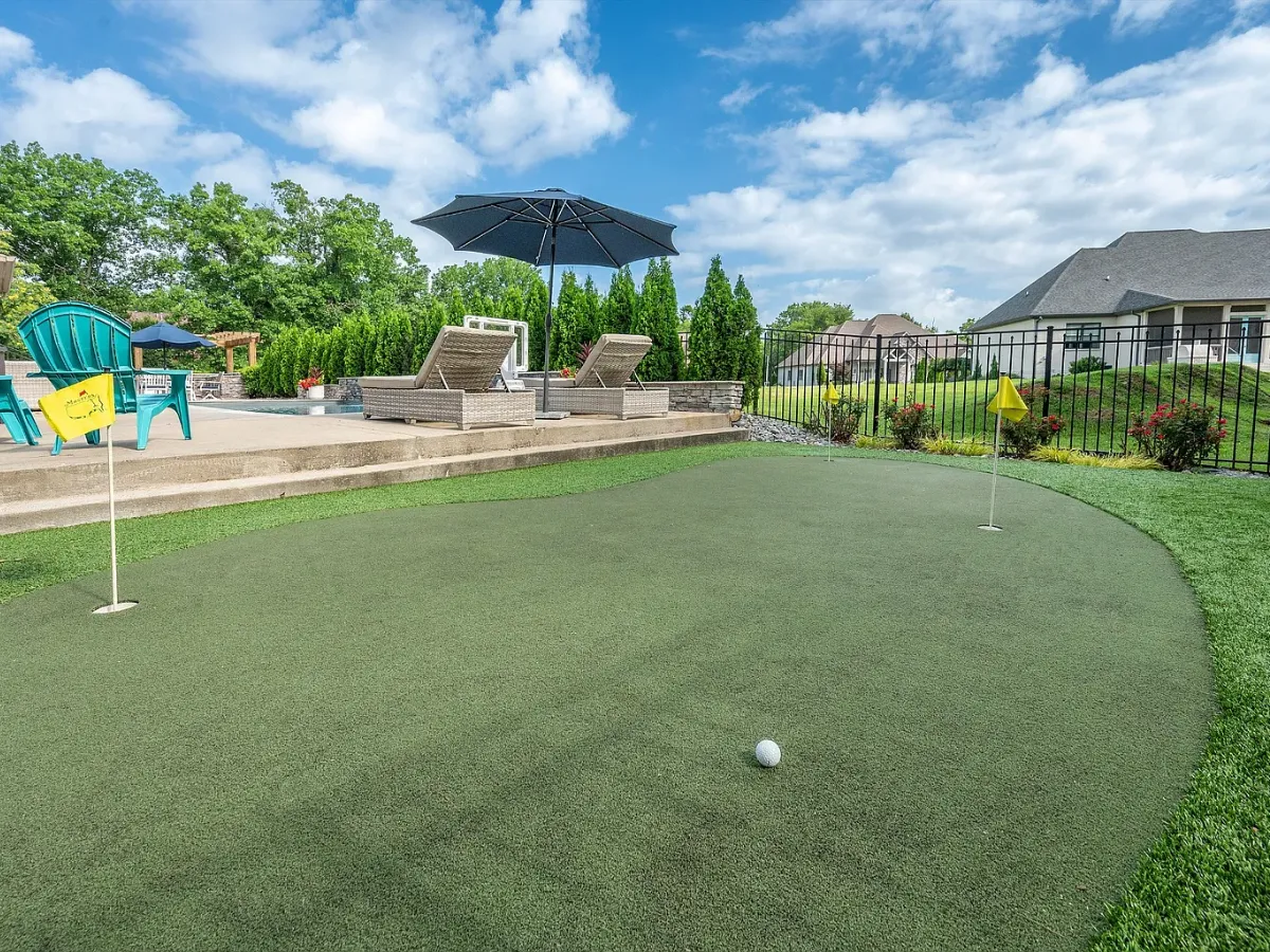 Multi-hole backyard putting green with flags beside a pool patio in Fort Mill, SC